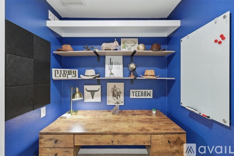 A room with a wooden desk and shelves with hats and other items.