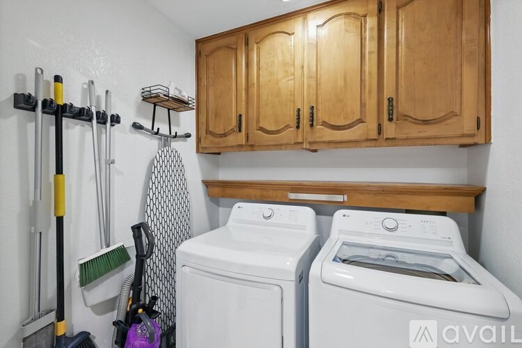 A laundry room with a washer and dryer and a broom.
