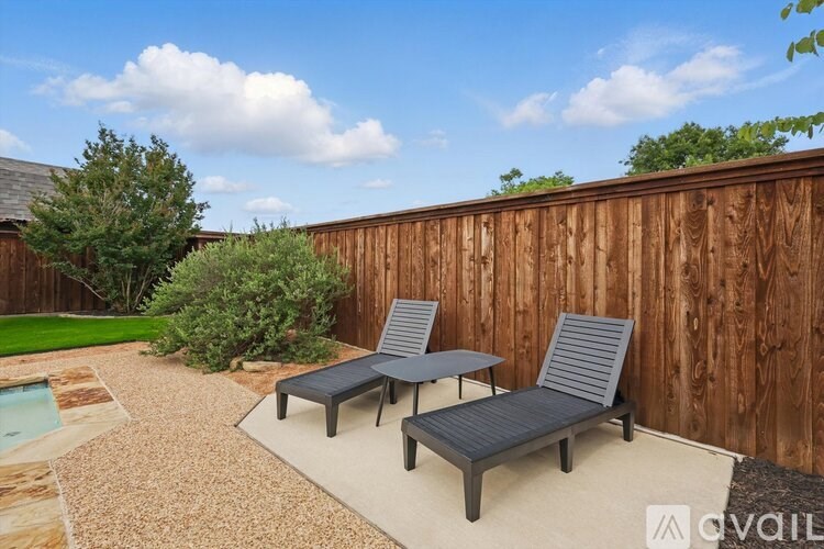 A backyard with a wooden fence, a table and two chairs.