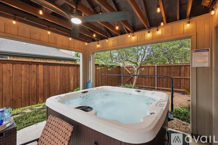 A hot tub is in a wooden enclosure with lights on the ceiling.