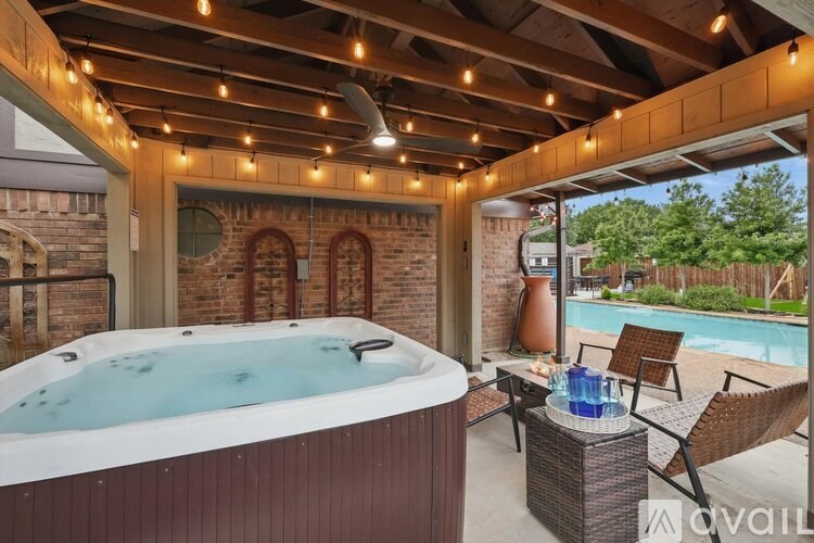 A hot tub is surrounded by chairs and a table with bottles on it.