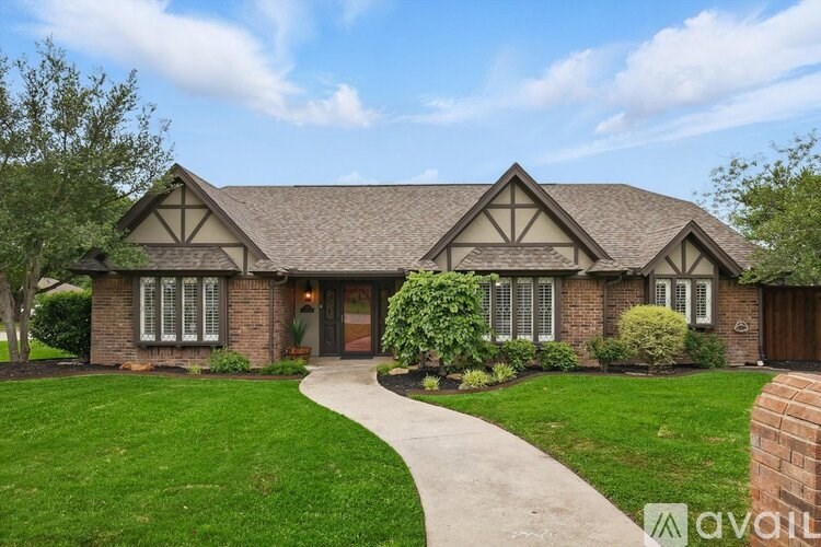 A house with a brown roof and a white door is surrounded by a green lawn.