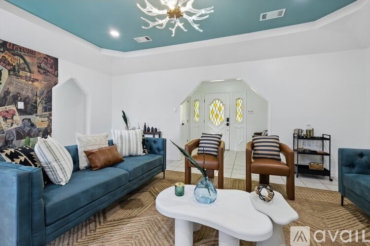 A living room with a blue couch, a white coffee table, and a chandelier.