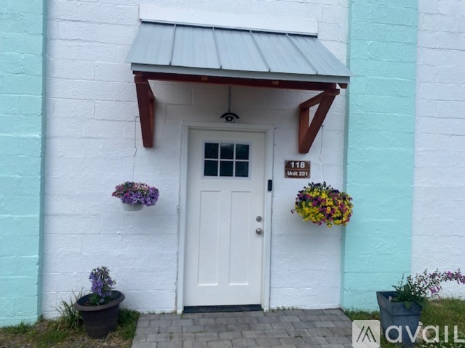 A white door with a sign above it and two hanging baskets of flowers.