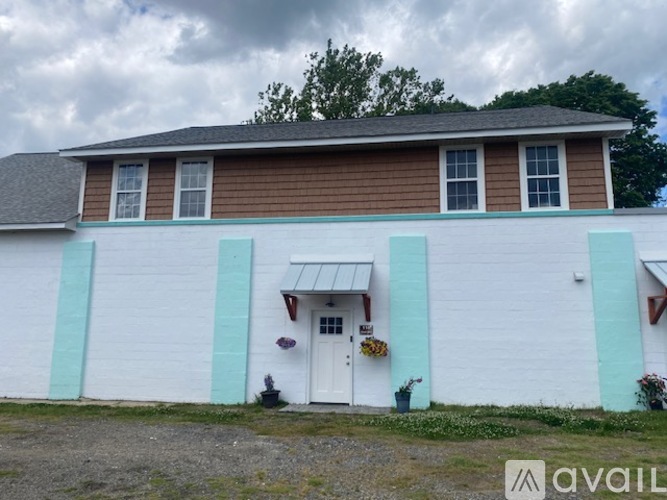 A white house with a brown roof and a blue trim.