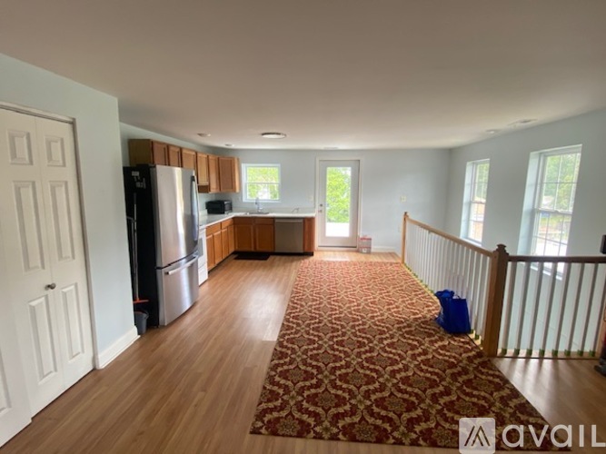 A kitchen with a refrigerator, sink, and a dining table with chairs.
