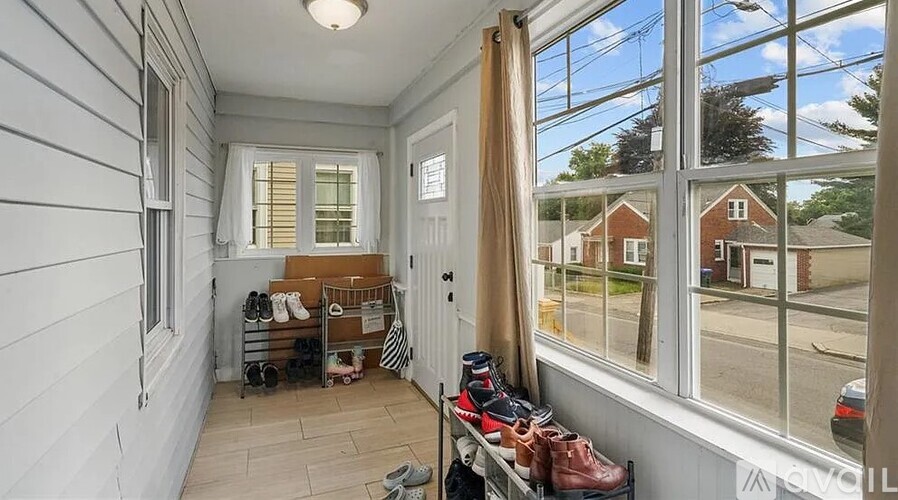 A room with a window overlooking a street with shoes on a shoe rack.