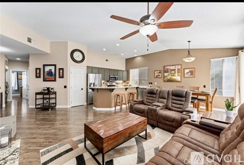 A living room with a brown leather couch and a ceiling fan.