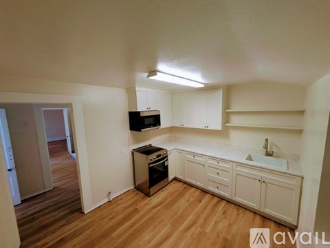 A kitchen with white cabinets and a wooden floor.