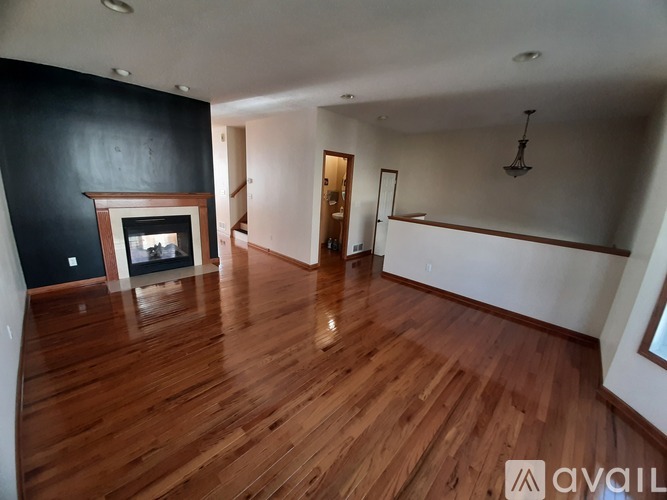 A spacious room with wooden flooring and a fireplace.