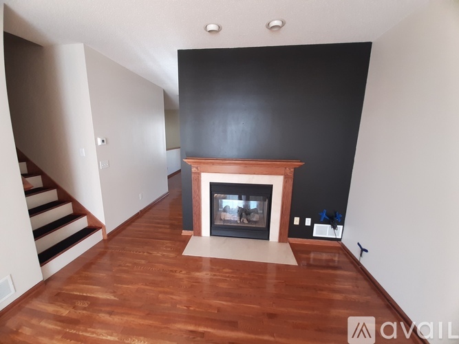 A living room with a fireplace and a staircase.
