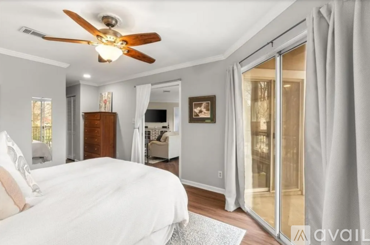 A bedroom with a white bed and a ceiling fan.