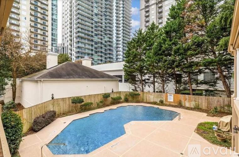 A small pool in a backyard with a wooden fence and a tree.
