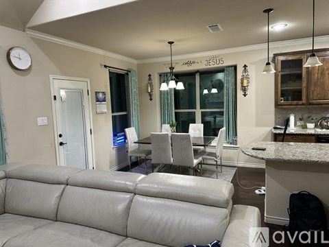 A living room with a grey sofa and a clock on the wall.