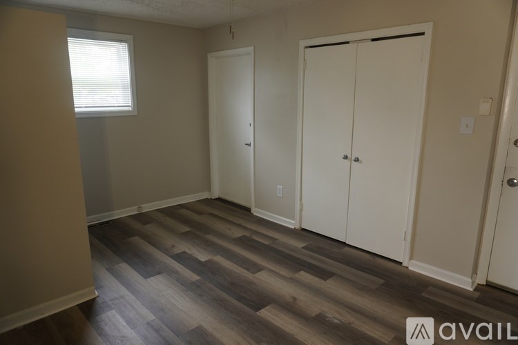 A room with wood flooring and white closet doors.