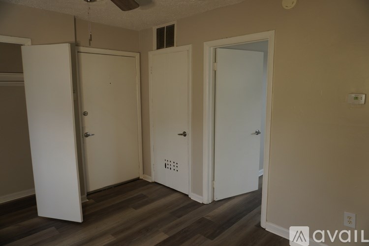 Three white doors are in a room with wood flooring.
