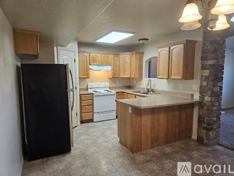 A kitchen with a black refrigerator and wooden cabinets.