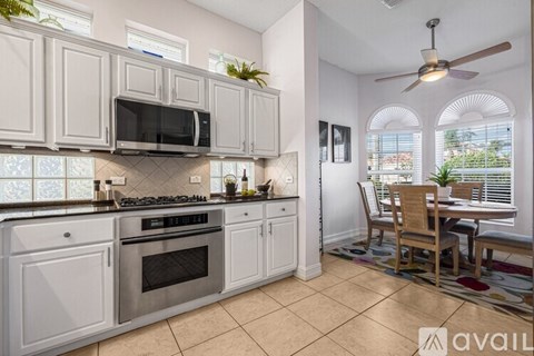 A kitchen with white cabinets and a tile floor.