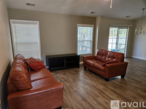 A living room with a brown leather couch and a red leather chair.