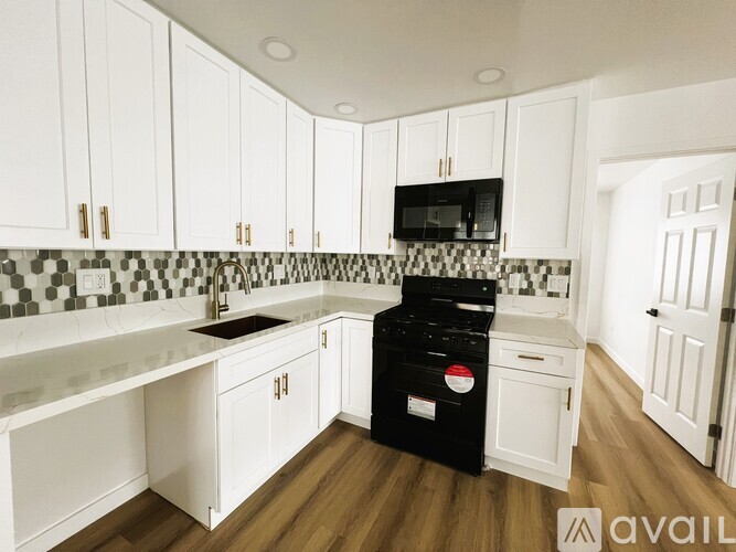 A kitchen with white cabinets and a black dishwasher.