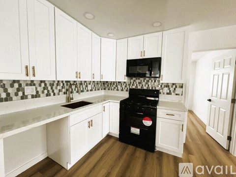 A kitchen with white cabinets and a black dishwasher.