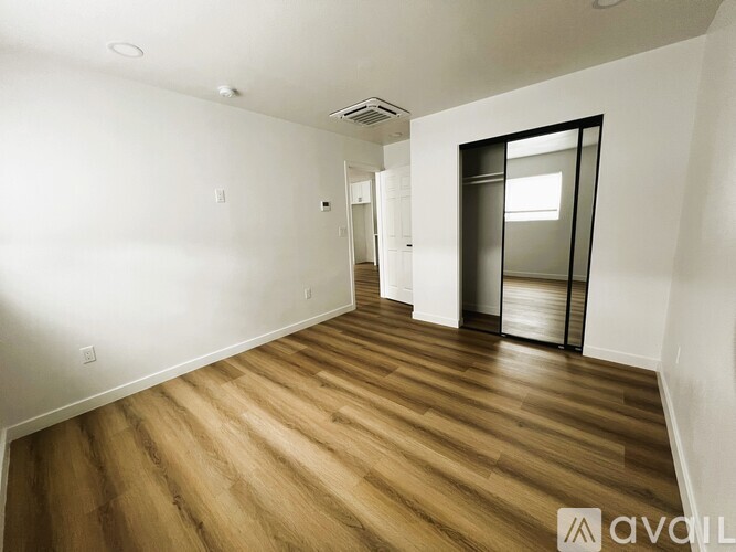 A room with wooden flooring and a glass door leading to another room.
