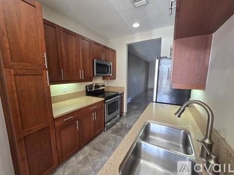 A kitchen with wooden cabinets and a stainless steel sink.