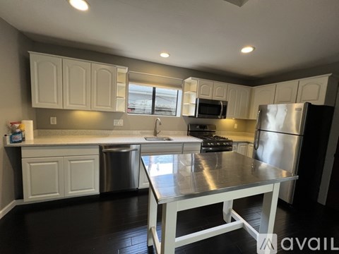 A kitchen with white cabinets and a stainless steel refrigerator.