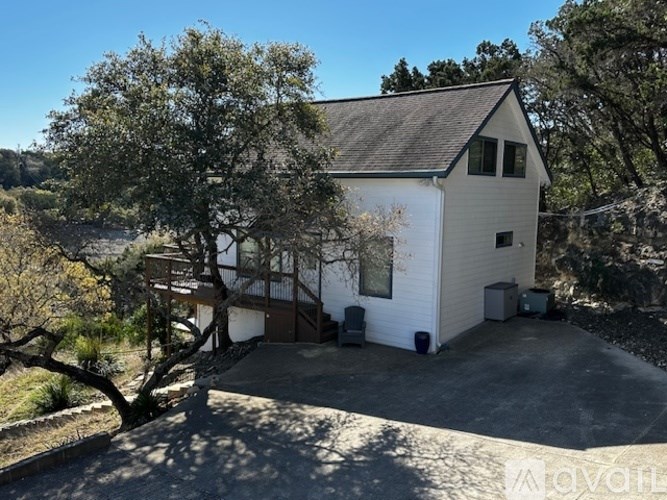 A white house with a black roof is surrounded by trees.