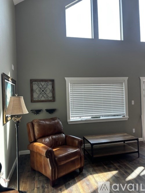 A brown leather chair is in front of a window with white blinds.