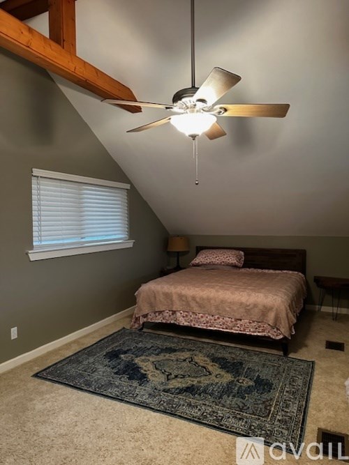 A bedroom with a bed, a rug, and a ceiling fan.