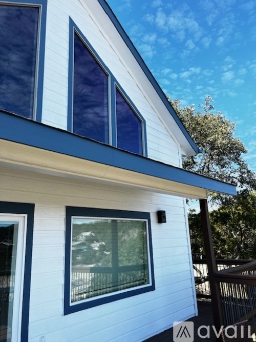 A house with a blue trim and white siding with a window and a balcony.