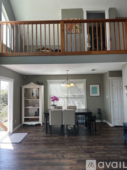 A dining room with a wooden floor and a balcony.