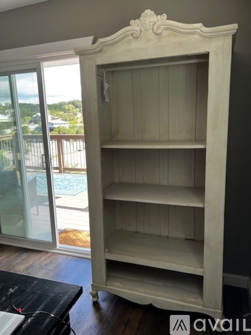 A white antique style bookcase with four shelves stands in a room.