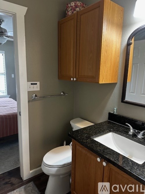 A bathroom with a toilet, sink and wooden cabinets.