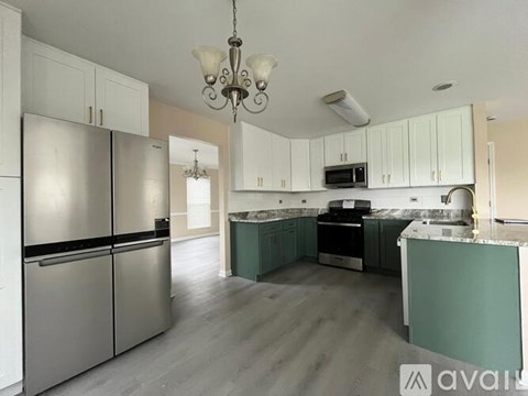 A kitchen with a refrigerator, microwave, and a chandelier.