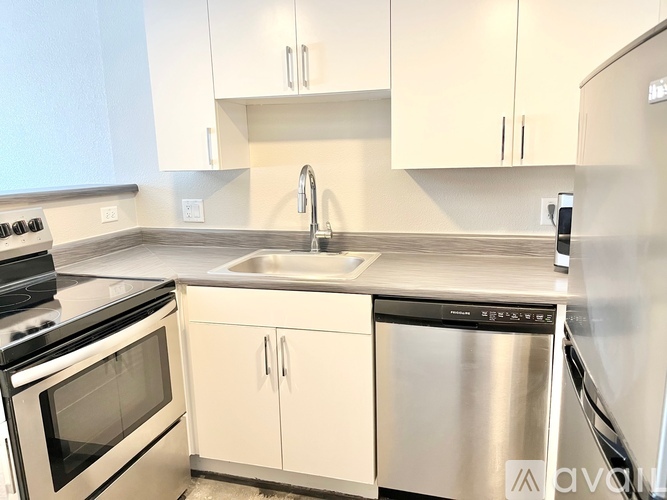 A kitchen with a stainless steel dishwasher and white cabinets.