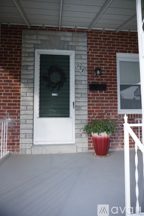 A red planter sits on a porch in front of a white door.