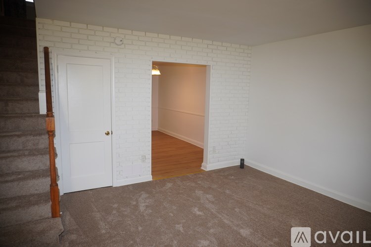 A room with a white door and a wooden staircase.