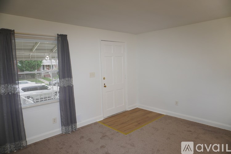 A room with a door, a window with curtains, and a carpet.