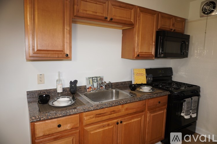A kitchen with wooden cabinets and a black microwave.