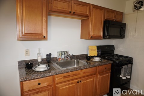 A kitchen with wooden cabinets and a black microwave.