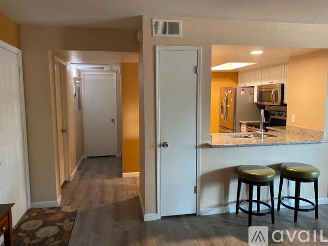 A kitchen area with a refrigerator, microwave, and stove is visible through a glass door.