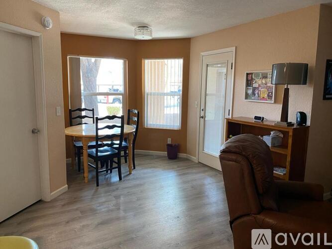 A living room with a brown leather chair and a wooden table with four chairs.