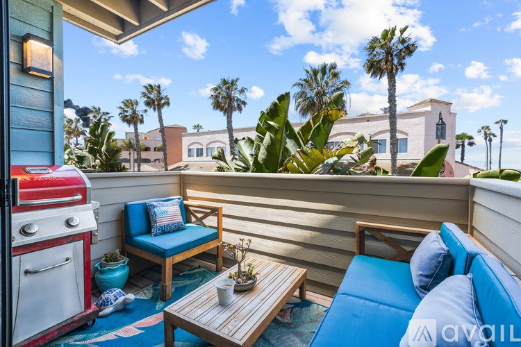 A sunny patio with a red grill and blue seating.