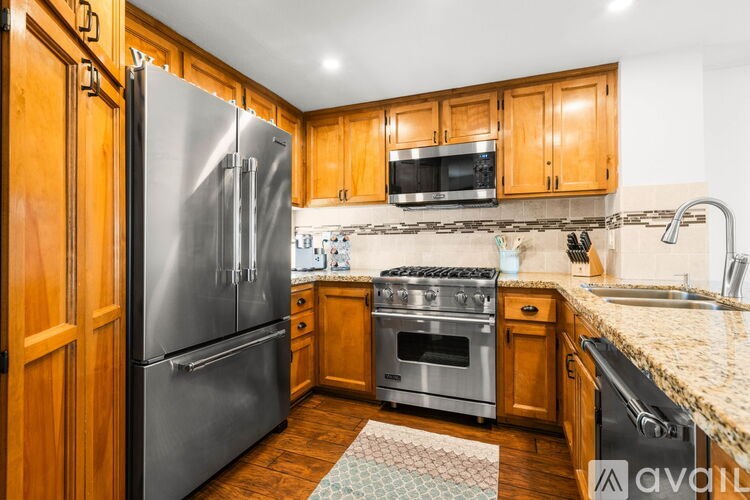 A kitchen with wooden cabinets and a stainless steel refrigerator.