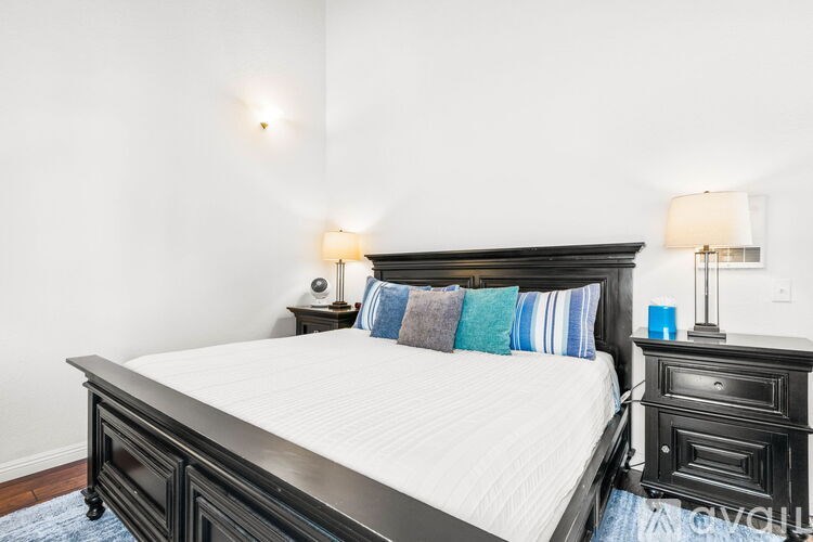 A bedroom with a large bed and a nightstand with a lamp.