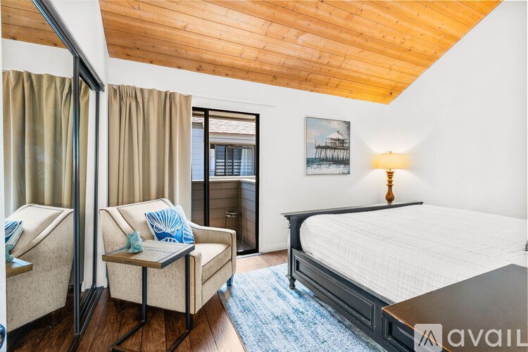 A bedroom with a bed, chair, and a painting on the wall.