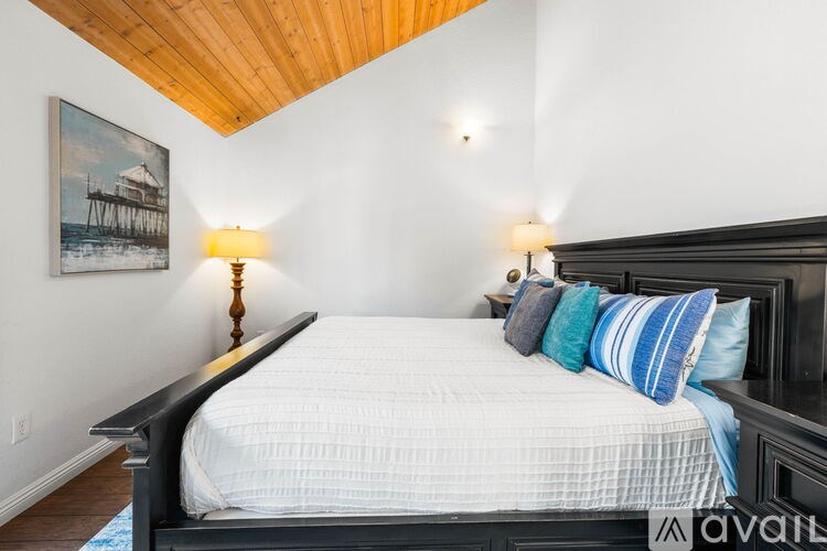 A bedroom with a bed, pillows, and a painting on the wall.