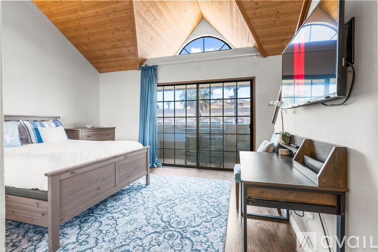 A bedroom with a bed, a table, and a window with a view.